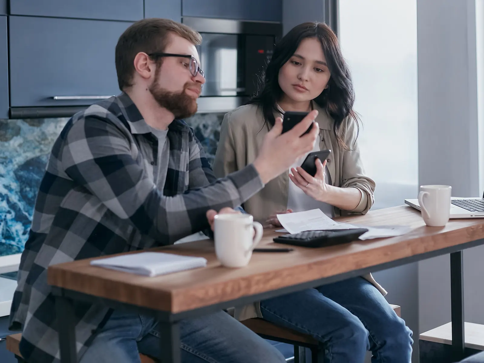 Two people at a kitchen table working out the week over one phone