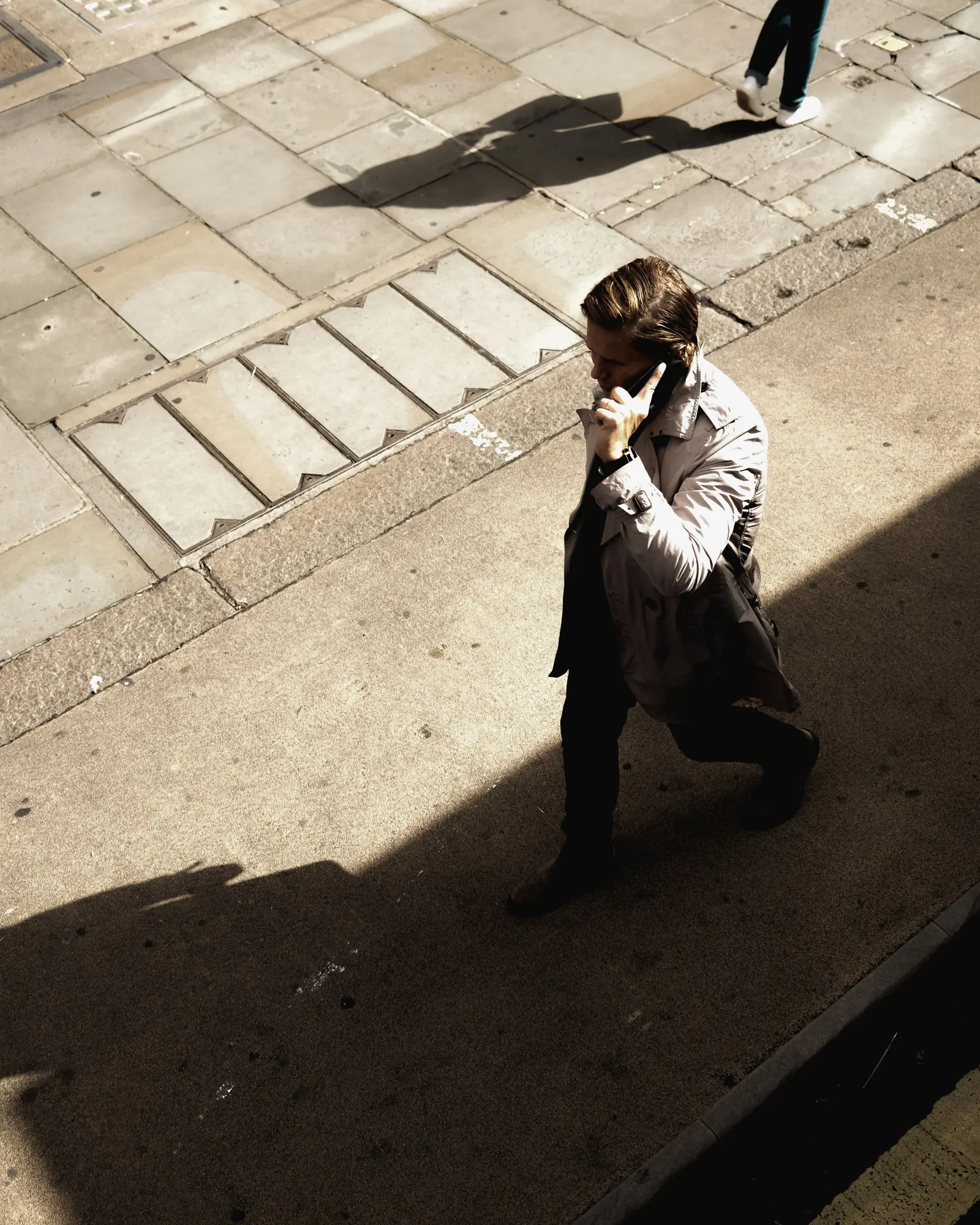 Walking between buildings on a bright morning with a phone in hand